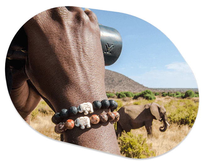 A hand wearing a Fahlo bracelet holding binoculars with an Elephant in a savanna on the background